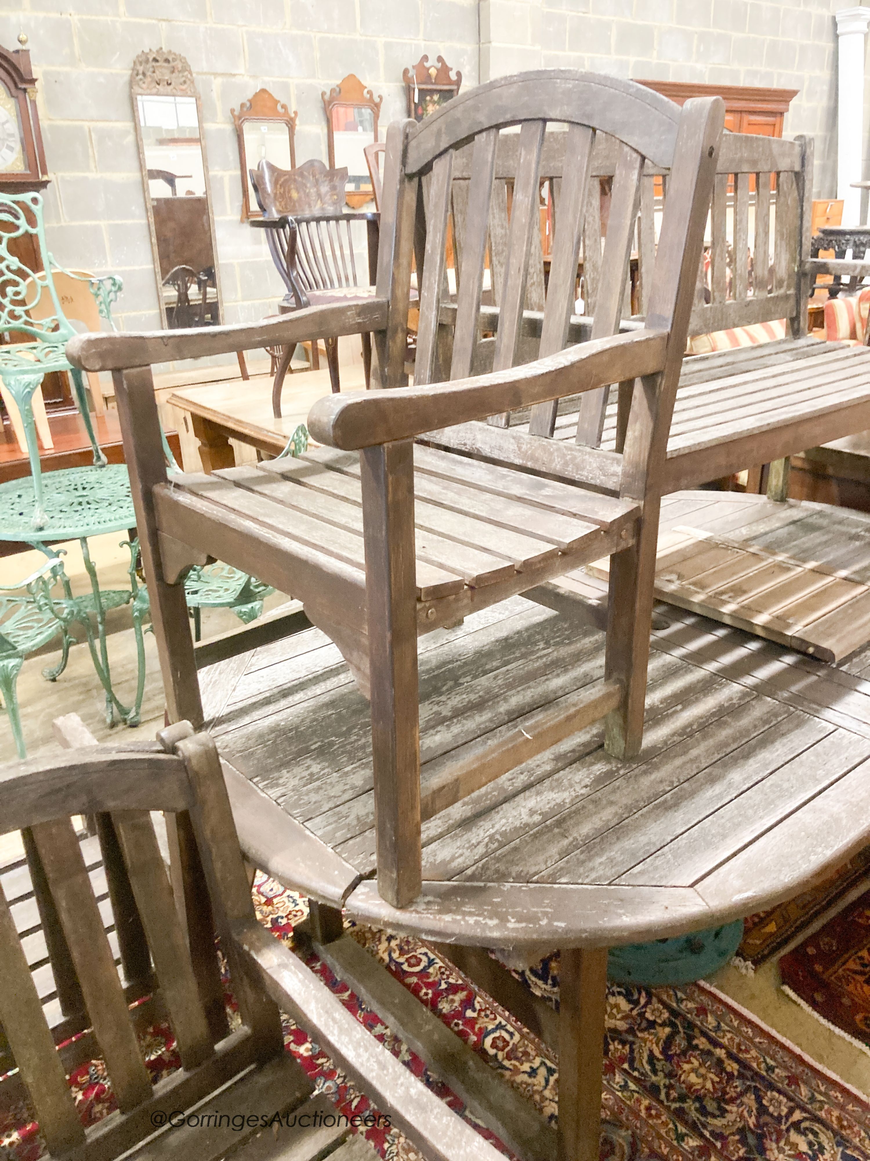 A weathered teak extending garden table, length 190cm, depth 120cm, height 74cm a bench and four weathered teak armchairs